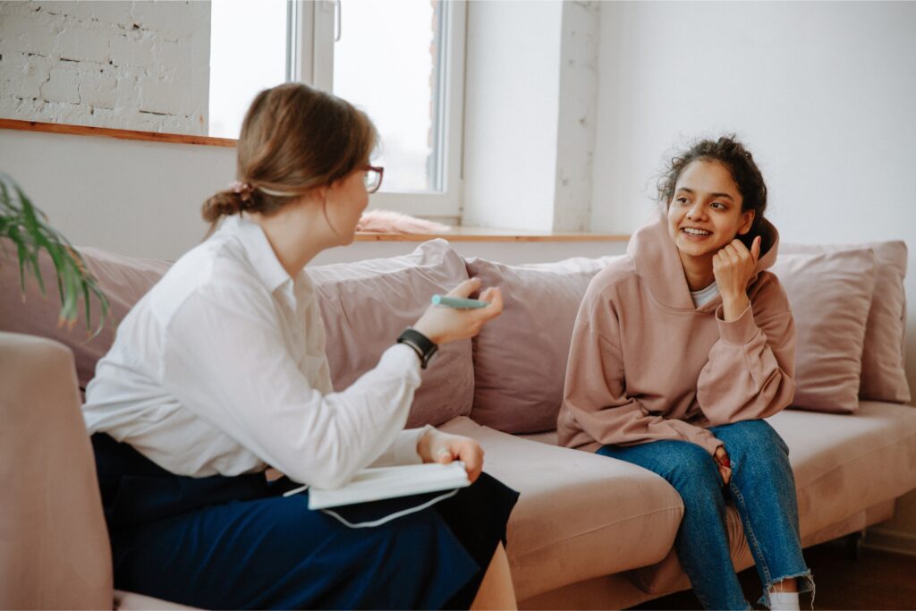 A woman at her therapist appointment sitting on the couch smiling and talking to the therapisttherapist 