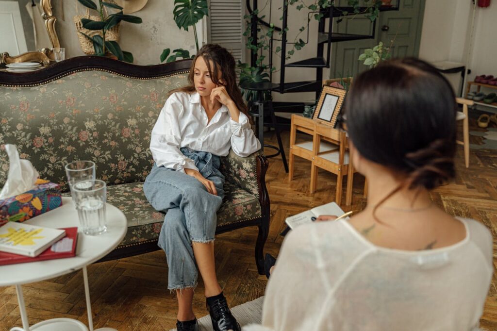 Woman in White Long Sleeve Shirt Sitting on Brown Wooden Chair